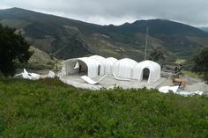 there are several tents set up in the grass with mountains in the backgroud