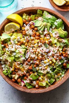 a wooden bowl filled with lettuce, chickpeas and garbanzo