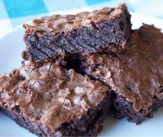 chocolate brownies stacked on top of each other on a white plate with blue checkered tablecloth