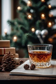 a glass of tea sitting on top of a book next to a christmas tree