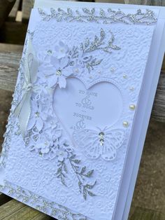 a white greeting card with silver embellishments and a heart on the front