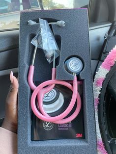 a pink stethoscope in a black box on top of a car seat