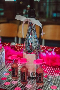 a table topped with bottles and confetti on top of a metal table cloth