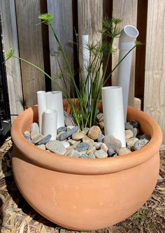 a planter filled with rocks and candles on top of a wooden fenced in area