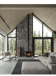 a living room with a couch, chair and fire place inside of it in front of large windows