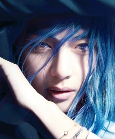 a young woman with blue hair and piercings on her arm is posing for the camera