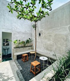 an outdoor area with benches, tables and a tree in the center is surrounded by concrete walls