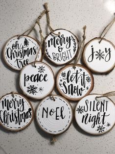 six christmas ornaments hanging from twine on a counter top with the words merry bright, let it snow and noel