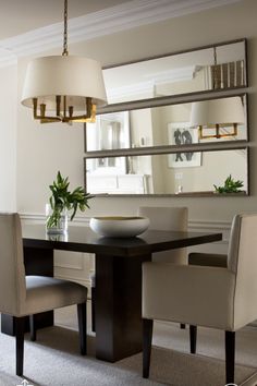 a dining room table with chairs and a mirror on the wall in front of it