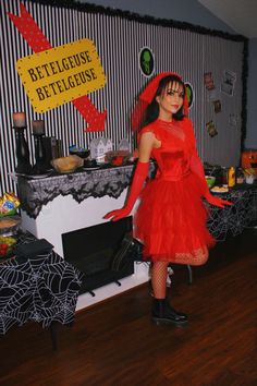 a woman in a red dress is standing near a table with halloween decorations on it