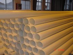 several white pipes stacked on top of each other in a room with windows behind them