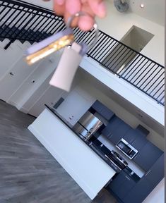 a person is holding something in their hand near the kitchen counter top and staircases