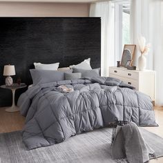 a bed with grey comforter and pillows in a bedroom