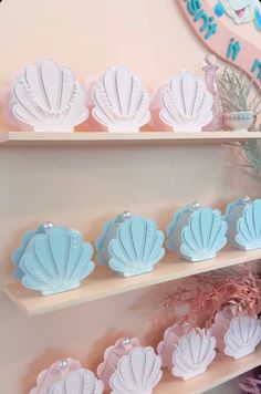 there are many seashells on the shelves in this store that is decorated with pink, blue and white colors