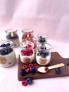 jars filled with berries and yogurt sit on a cutting board