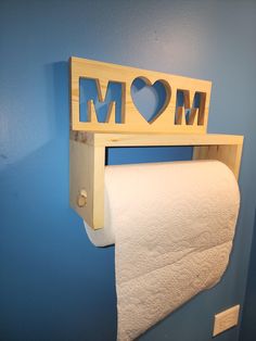 a wooden sign that says mom above a roll of toilet paper on a rack in a bathroom