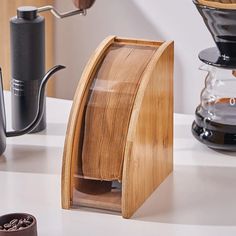 a wooden coffee maker on a counter next to some cups