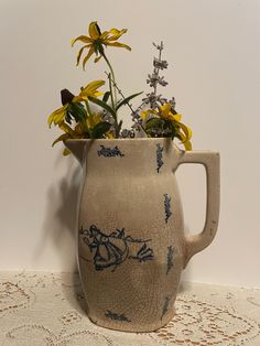 a vase filled with yellow flowers on top of a lace tablecloth covered floor next to a white wall