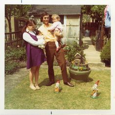 a man and two women are holding a baby in their arms while standing on the lawn