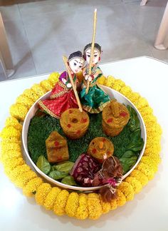 an arrangement of flowers and figurines in a bowl on a white table top