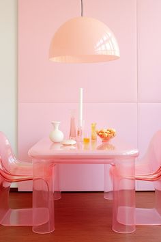 a pink dining room with chairs and a table in front of a large light fixture