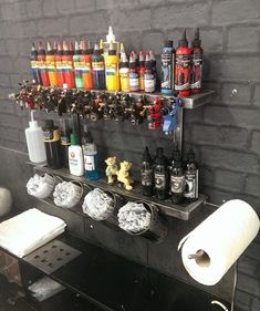 there are many bottles on the shelf next to the toilet paper roll and other items