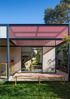 a pink and blue building sitting on top of a lush green field next to trees