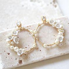 two gold hoop earrings with white pearls and crystal stones on a marble slabd surface