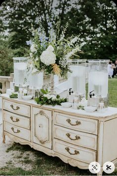 an old dresser with flowers and candles on it