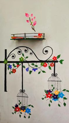 a birdcage with flowers painted on the side of it and a shelf above it