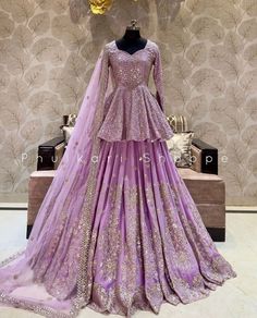 a purple gown on display in front of a wallpapered room with gold accents