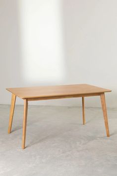 a wooden table sitting on top of a cement floor next to a white wall in an empty room