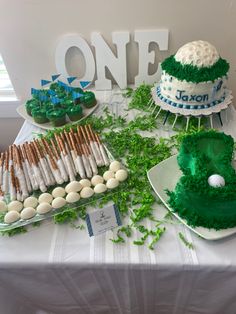 a table topped with cakes and cupcakes covered in green frosting