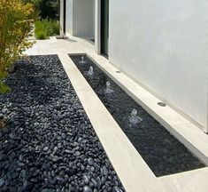 a modern house with a water feature in the front yard