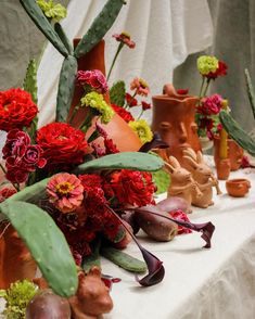 a table topped with lots of vases filled with different types of flowers and plants