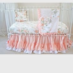 a crib bed with pink and white ruffled bedspread