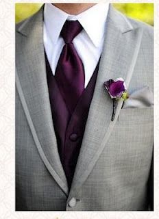 a man wearing a suit and tie with a purple flower in his lapel pocket