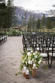 an outdoor ceremony set up with white flowers and greenery on the back of chairs