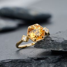 a yellow diamond ring sitting on top of a rock