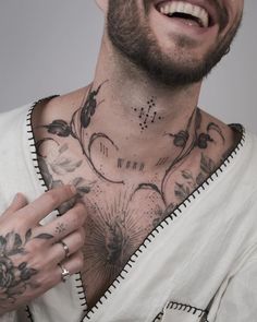 a man with tattoos on his chest smiling