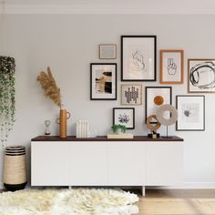 a living room with white furniture and lots of pictures on the wall, including plants