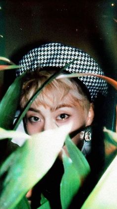 a woman is peeking out from behind some plants