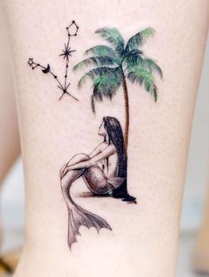 a woman sitting under a palm tree tattoo on her lower leg with stars and moon in the background