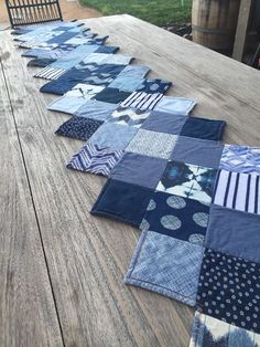 several pieces of blue quilt laid out on a wooden table with chairs in the background