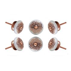 four white and copper knobs with flowers on the top one has a rosette design