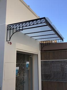 a white building with a black metal roof over it's door and window sill