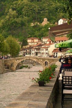 people sitting at tables on the side of a river