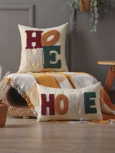 two decorative pillows sitting on top of a wooden floor next to a basket and potted plant