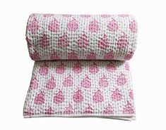 two pink and white bedspreads on top of each other, one is folded up