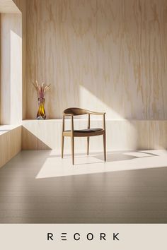 a wooden chair sitting in the middle of a room next to a vase with flowers